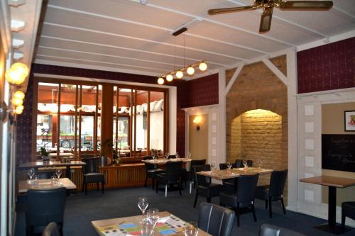 una sala da pranzo con tavoli, sedie e finestre di Hotel Le Limbourg a Rochefort