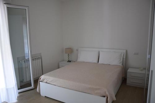 a white bedroom with a bed and a mirror at el Capitan de Mar in Chioggia