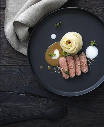 een bord met vlees en pasta op tafel bij Le Boutique Danang in Da Nang