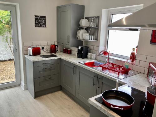 a kitchen with gray cabinets and a red sink at Plymouth Hoe Hideaway in Plymouth