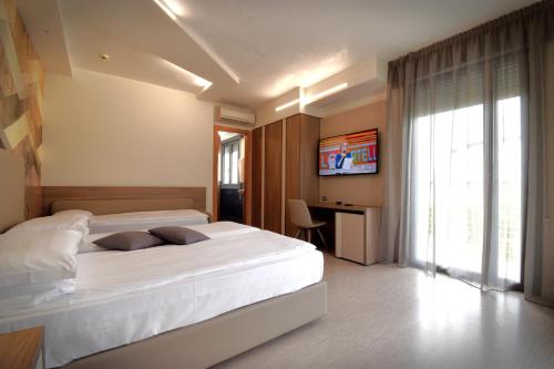 a bedroom with a bed and a desk and a television at Hotel Delle Nazioni - Adults Only in Caorle
