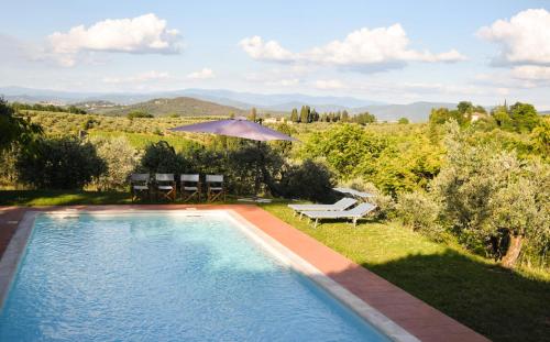 a swimming pool with a table and an umbrella at Tenuta Massabò in San Casciano in Val di Pesa