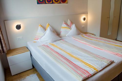 a bedroom with a white bed with colorful pillows at Garni Meinrad in Ora/Auer