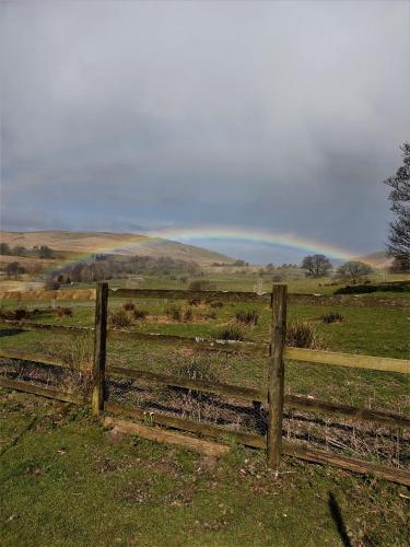 a fence in a field with a rainbow in the background at Elysian Fields @ Ing Hill Lodge in Outhgill