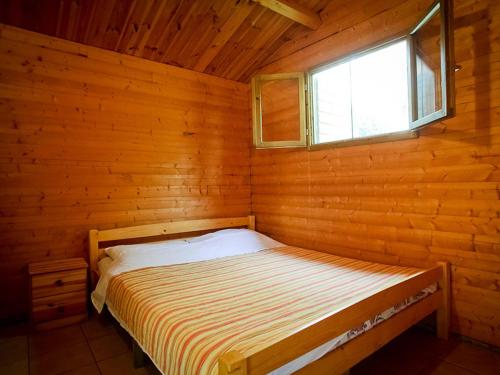 Bungalows Starine Tribunj في تريبونج: سرير في غرفة خشبية مع نافذة