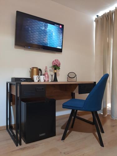 a desk with a blue chair and a television on a wall at Petra Rooms and Apartments in Rab