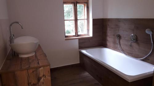 a bathroom with a tub and a sink and a window at Plötzhof in Hof bei Salzburg