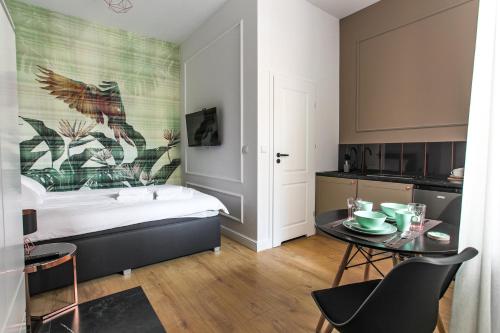 a bedroom with a bed and a table and a kitchen at Ara Apartamenty in Toruń