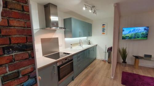 a kitchen with blue cabinets and a brick wall at Chambers Apartment @ The Old Magistrates in Betws-y-coed