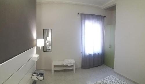 a white bathroom with a window and a chair at HOTEL MALIBU in Spotorno