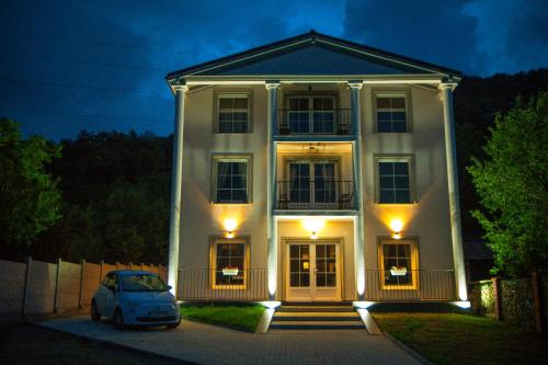 a white house with a car parked in front of it at Green Hill Villa & SPA in Călimăneşti