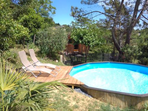 a swimming pool on a wooden deck with two lounge chairs at La cabane en bois in Villemur-sur-Tarn