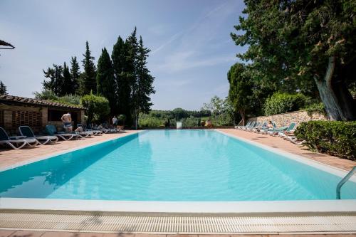 a large swimming pool with chairs and trees at Hotel Pescille in San Gimignano
