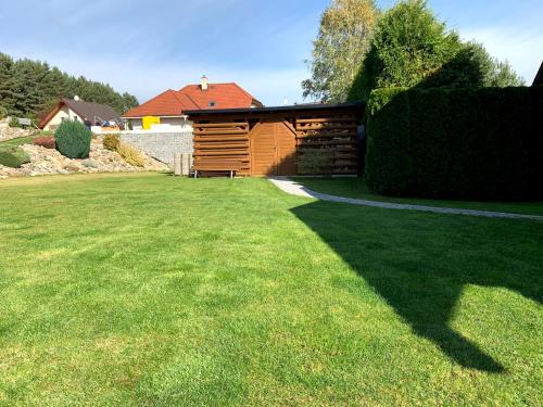 a wooden shed in a yard with a lawn at Ubytování v Kamenném zákoutí in Česká Ves