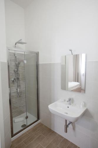 a white bathroom with a sink and a shower at B&B La mia Isola in Castelluzzo