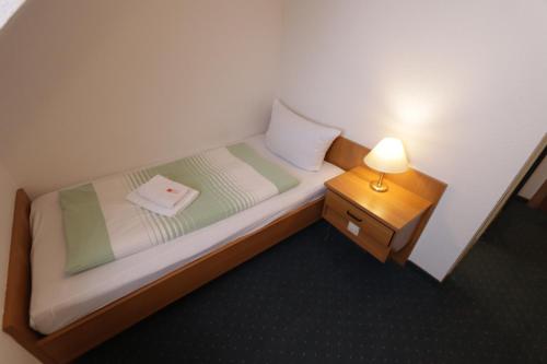 Cama pequeña en habitación pequeña con lámpara en Hotel Riedel, en Zittau