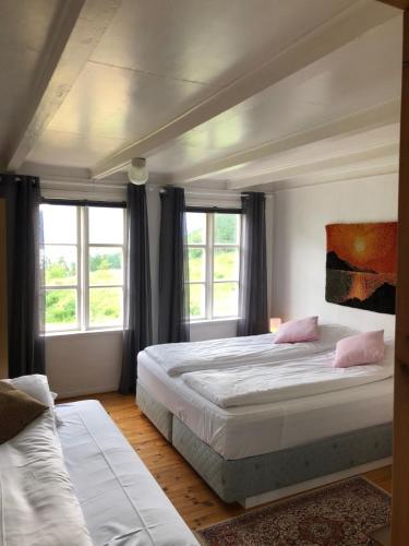 a bedroom with two beds and two windows at Tunold Gård - Gamle huset in Mindresunde