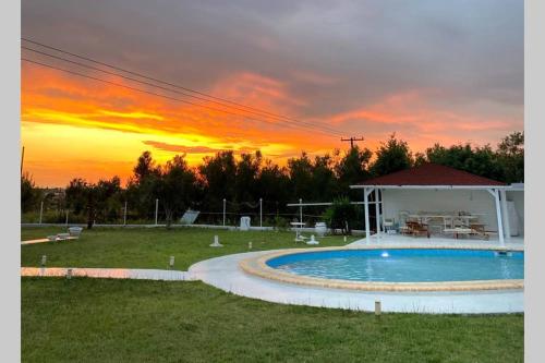 a pool in a yard with a sunset in the background at Family Maisonette with pool #2 in Nea Fokea