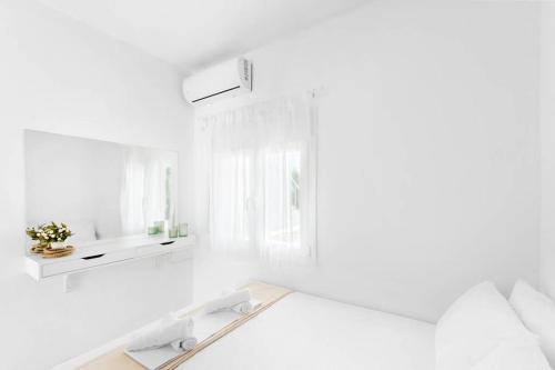 a white room with a bed and a mirror at Family Maisonette with pool #2 in Nea Fokea