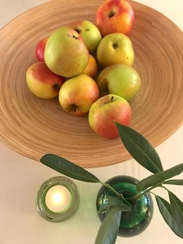 a bowl of apples on a plate with a candle at Hotell Bäckagården in Ystad