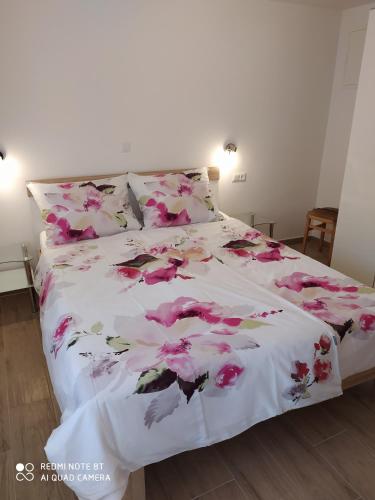 a bed with a white blanket with pink flowers on it at Apartment Bruno in Mali Lošinj