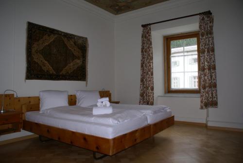 a bedroom with a large white bed with a window at Historisches Hotel Piz Ela Bergün in Bergün