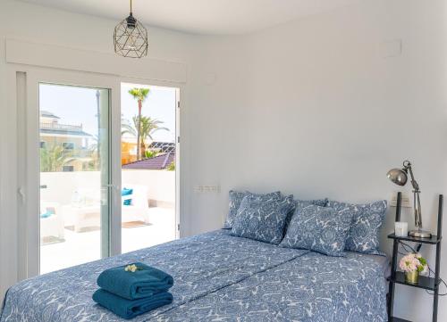 a bedroom with a bed with a blue comforter at Beach Villa Playa Flamenca in Orihuela Costa