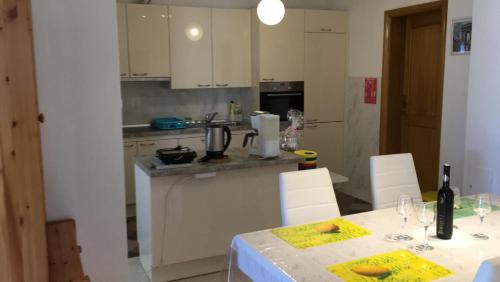 uma cozinha com uma mesa com cadeiras brancas e um balcão em Apartment Novi Vinodolski em Novi Vinodolski
