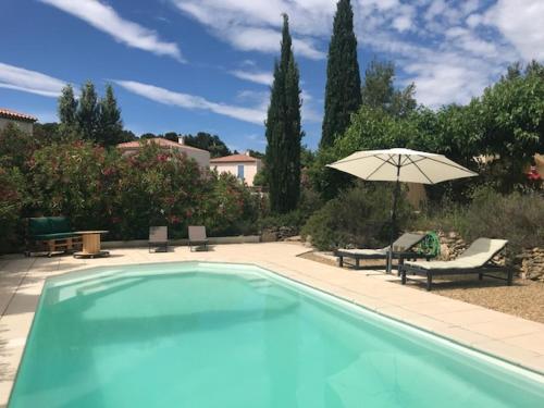 une piscine avec un parasol, une table et des chaises dans l'établissement Duplex pour 2 à 4 personnes avec piscine au coeur des vignes, à Pélissanne