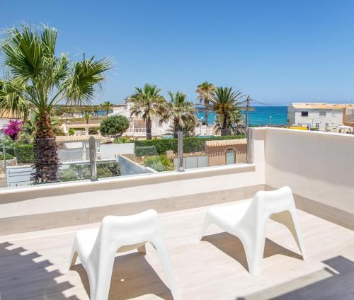 two white chairs on a balcony overlooking the ocean at Beach Villa Flamenca in Orihuela