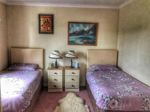 two beds in a bedroom with purple comforter at Niblick in Bantry