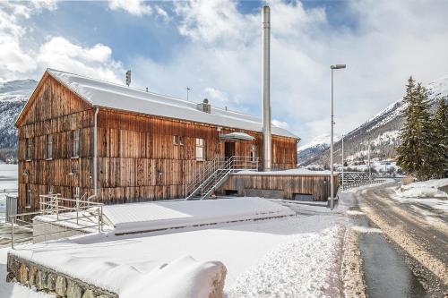 a wooden building with snow on the ground at Madulain Lodge @ Werkhof in Madulain