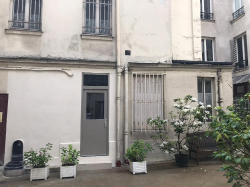 ein weißes Gebäude mit einer Tür und einigen Pflanzen in der Unterkunft Studio - Central Paris in Paris