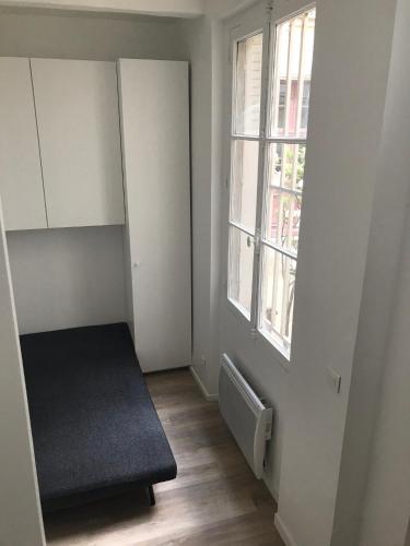 ein leeres Zimmer mit einem Bett und einem Fenster in der Unterkunft Studio - Central Paris in Paris