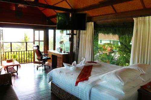 a bedroom with a bed and a desk and a television at Glass Cottage in Wok Tum
