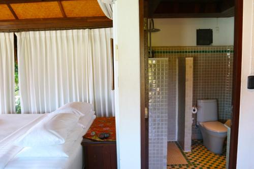 a bedroom with a bed and a bathroom with a toilet at Glass Cottage in Wok Tum