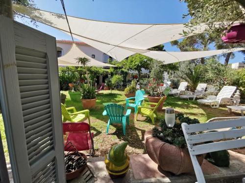 a garden with chairs and tables and a white umbrella at Hôtel Punta e Mare des Chambres ou des Appartements T2 in Cargèse