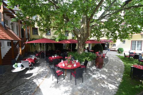 an outdoor restaurant with tables and chairs under a tree at Hotel Payerbacherhof in Payerbach