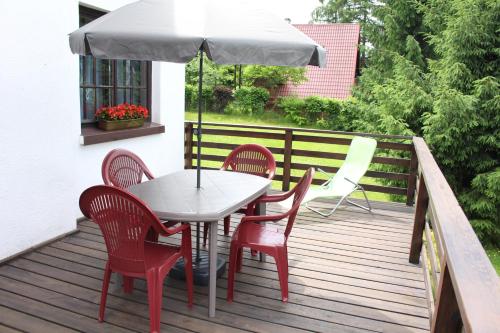 a table and chairs on a deck with an umbrella at Domek Letniskowy nad Jeziorem Tumiany in Bartołty Wielkie