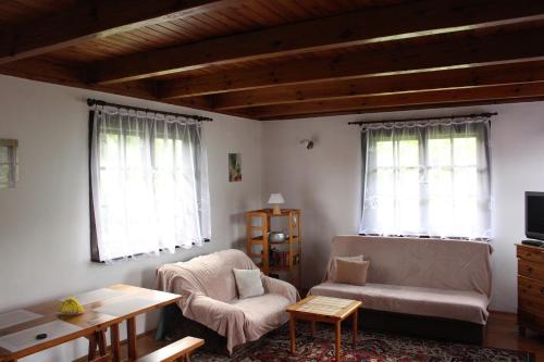 uma sala de estar com um sofá, uma cadeira e 2 janelas em Domek Letniskowy nad Jeziorem Tumiany em Bartołty Wielkie