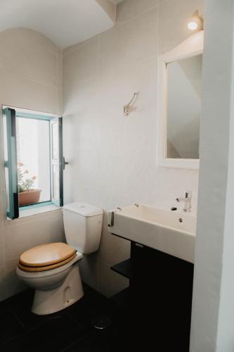 a white bathroom with a toilet and a sink at Casa Calle Real 87 in Frigiliana
