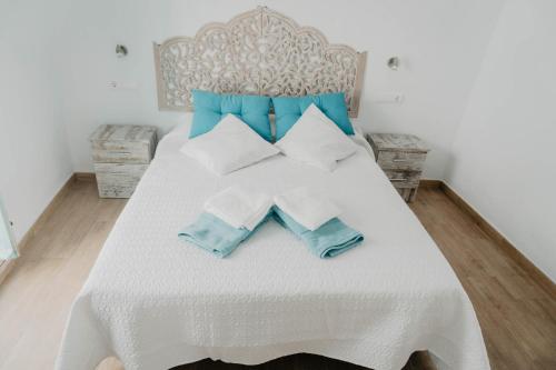 a bed with blue and white pillows on it at Casa Calle Real 87 in Frigiliana
