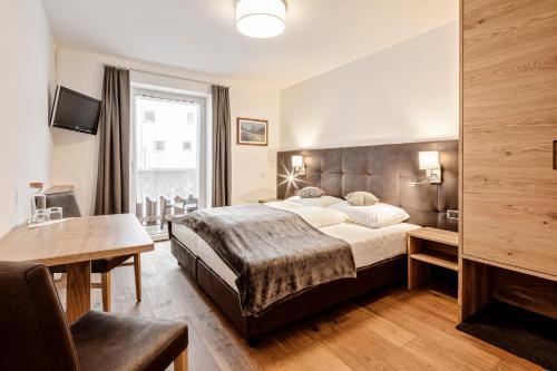 a bedroom with a large bed and a desk at Garni Charlotte in Selva di Val Gardena