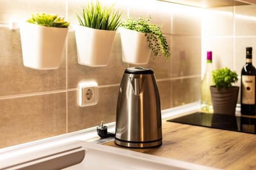 a coffee pot on a kitchen counter with potted plants at Apartman Modena Lux in Vrnjačka Banja
