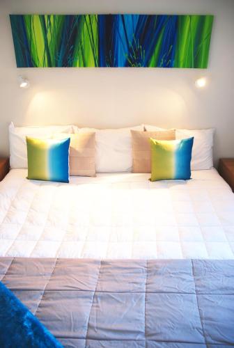 a large bed with blue and yellow pillows on it at Almond Court Motel in Alexandra