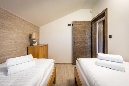 two beds in a small room with a door at Horská Chata Ostružiny in Donovaly