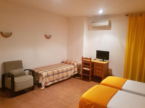 a room with two beds and a chair and a television at Can Panxeta in Pallaresos