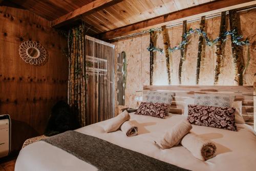 1 dormitorio con 1 cama blanca grande con almohadas en DURMIENDO ENTRE ARBOLES, Bonita cabaña en La Rioja, en Anguciana