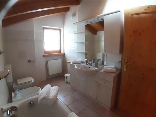 a bathroom with two sinks and two toilets and a window at Appartamento 3cime Stefania in Padola