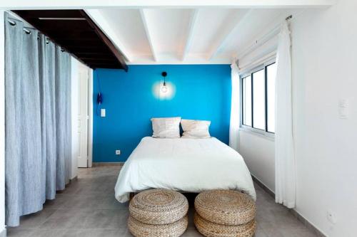 una camera da letto con un letto con pareti e sgabelli blu di AZUR a Le Diamant